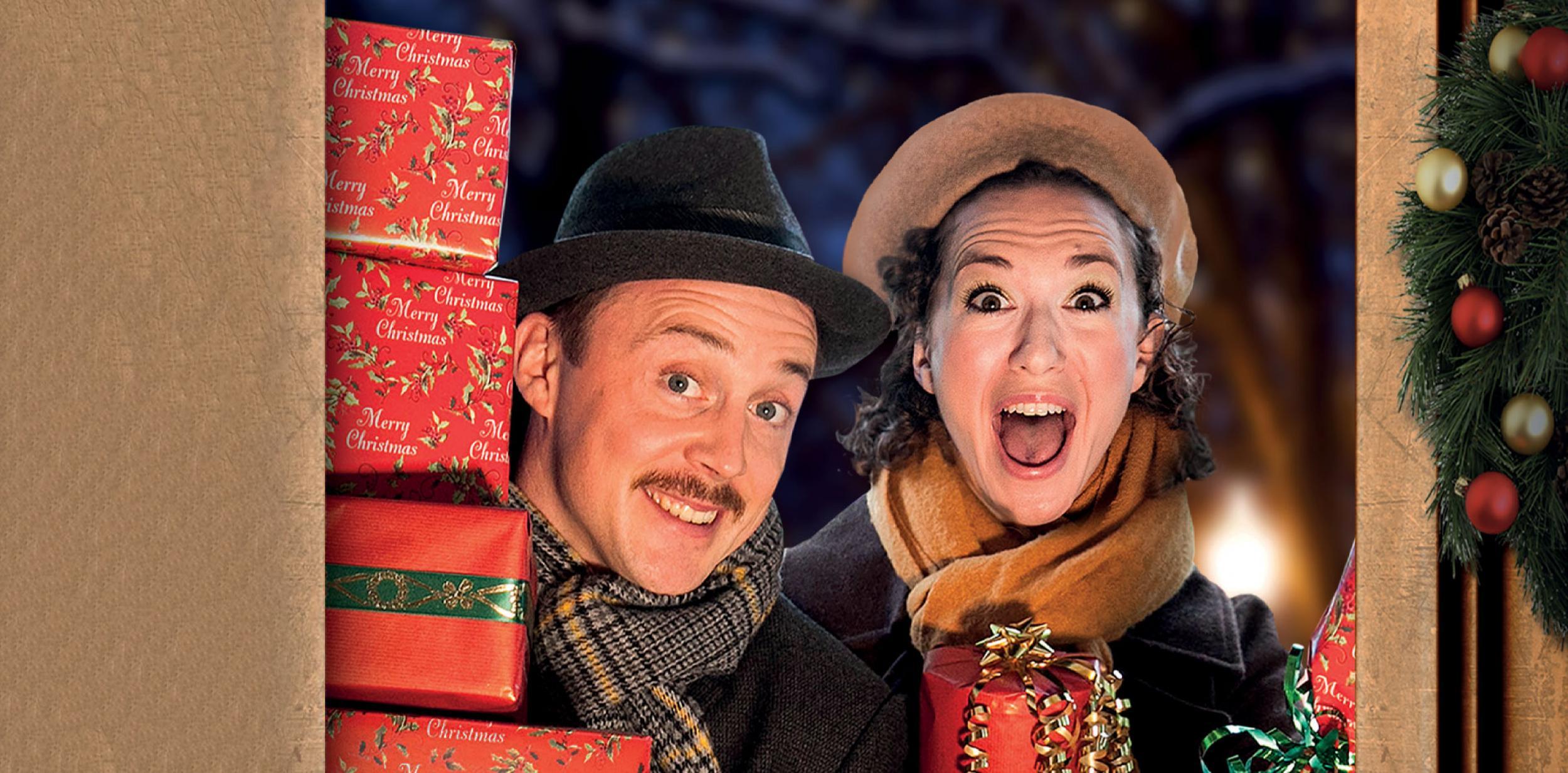 A man and a woman at the front door smiling and carrying a stack of Christmas presents