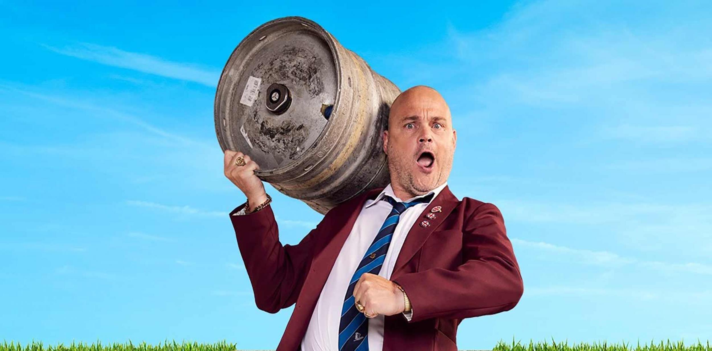 Al Murray carrying a beer barrel on his shoulder