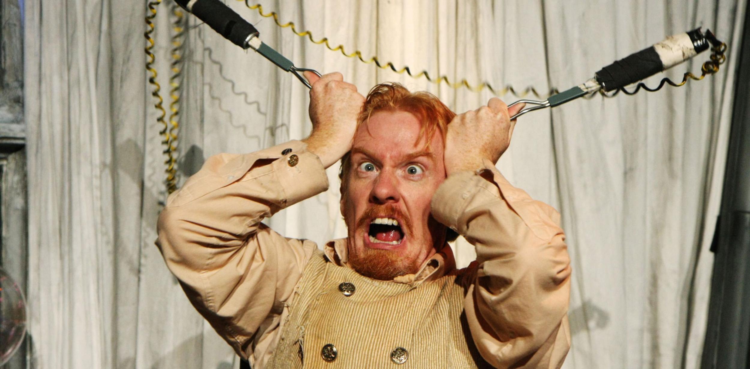 Comedic man holding electricity cable to his head