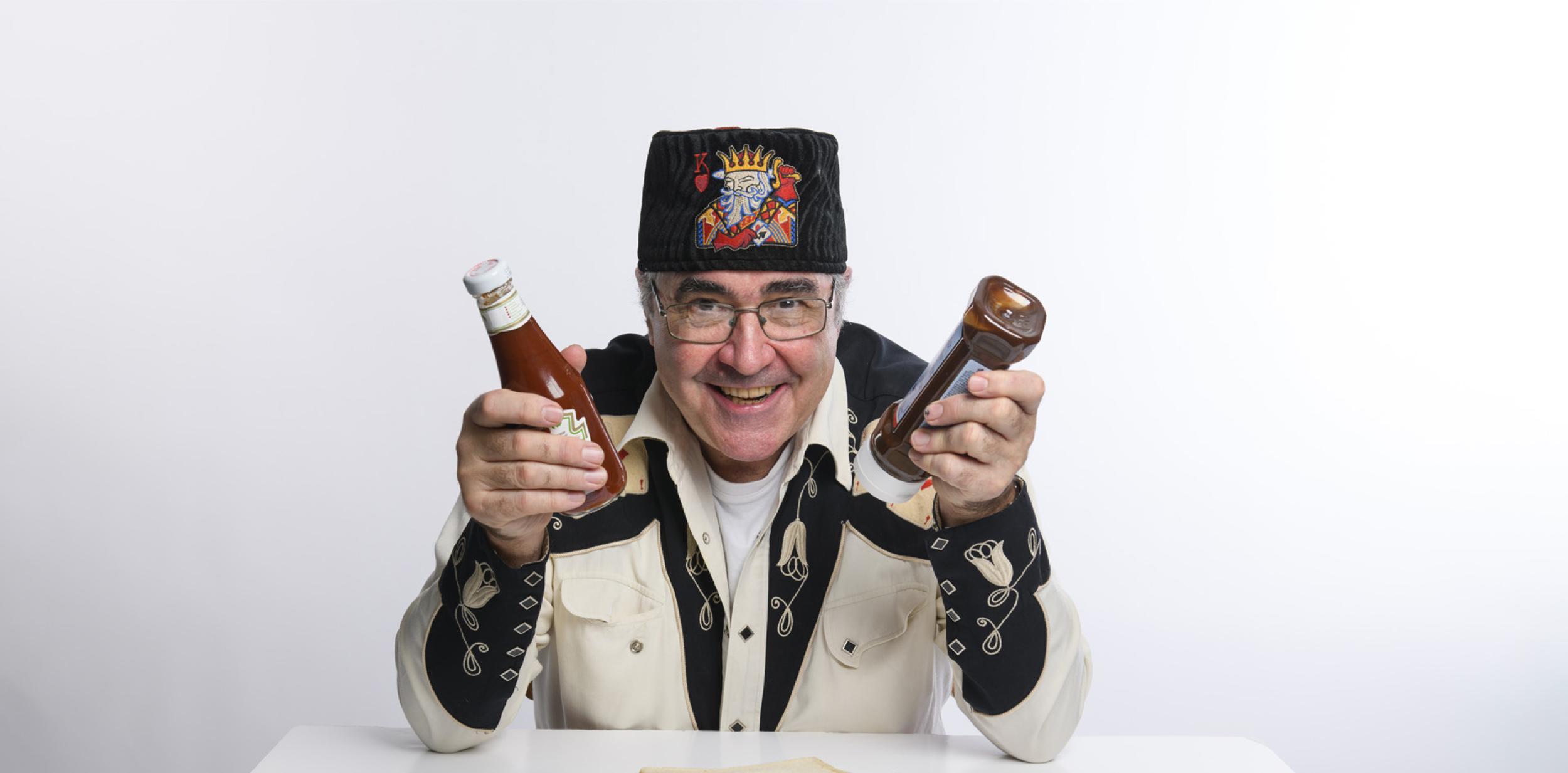 Danny Baker holding up sauce bottles