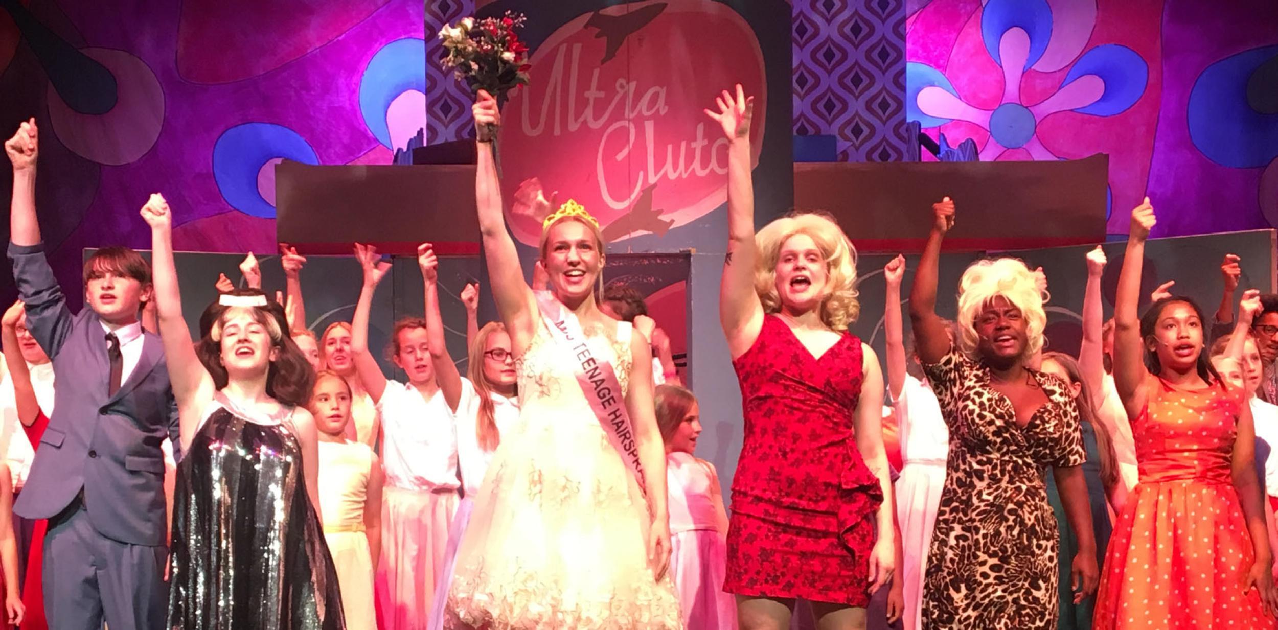 Young people on stage with their arms in the air