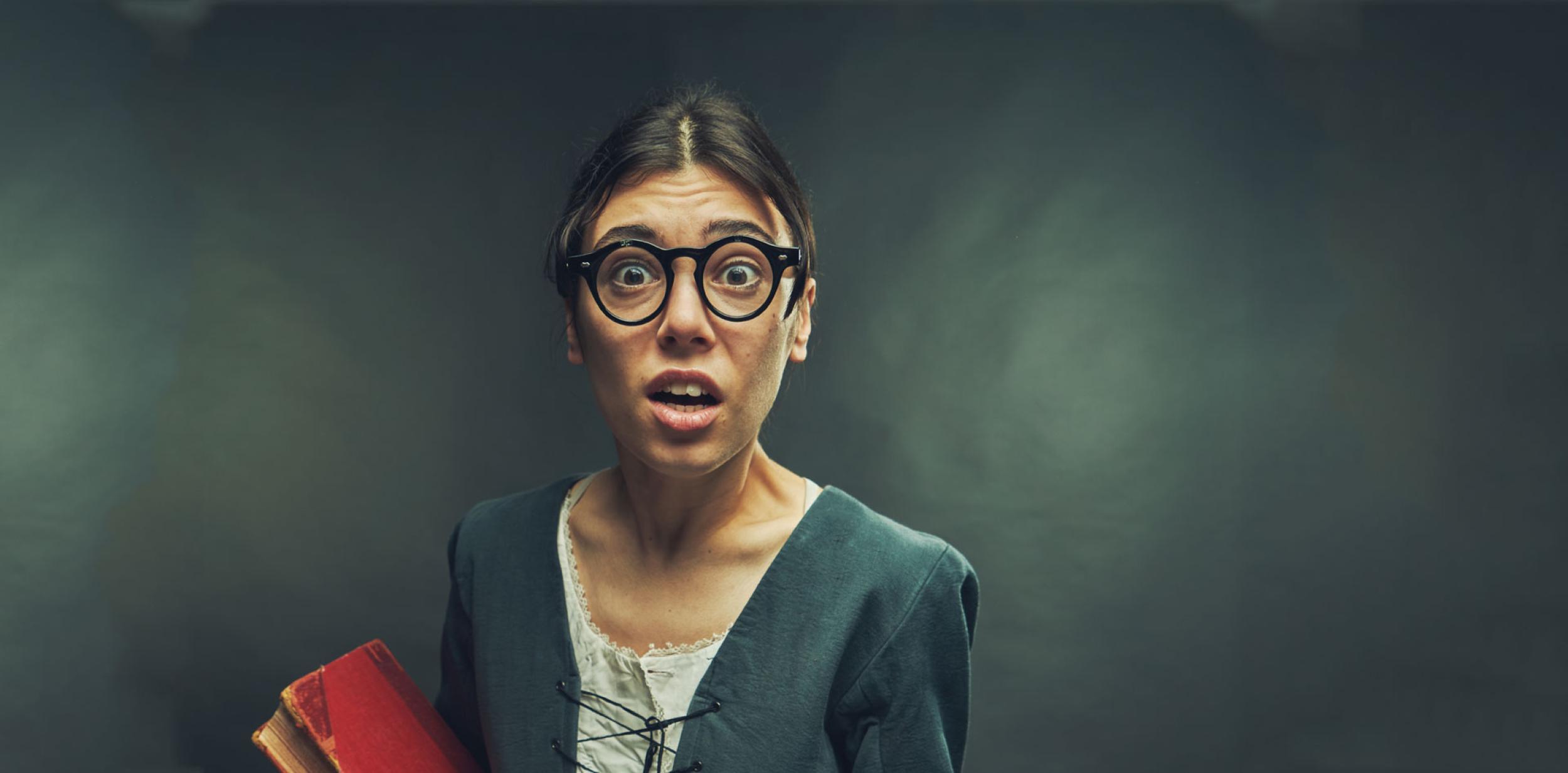 Person wearing glasses holding a book