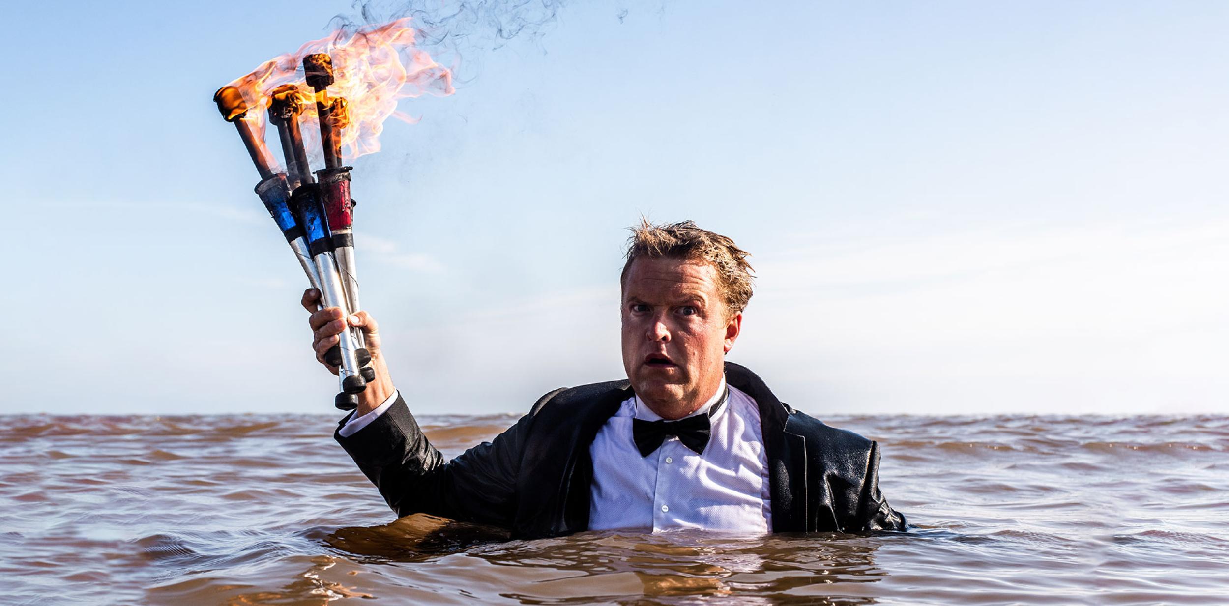 Person in the sea with flaming juggling clubs