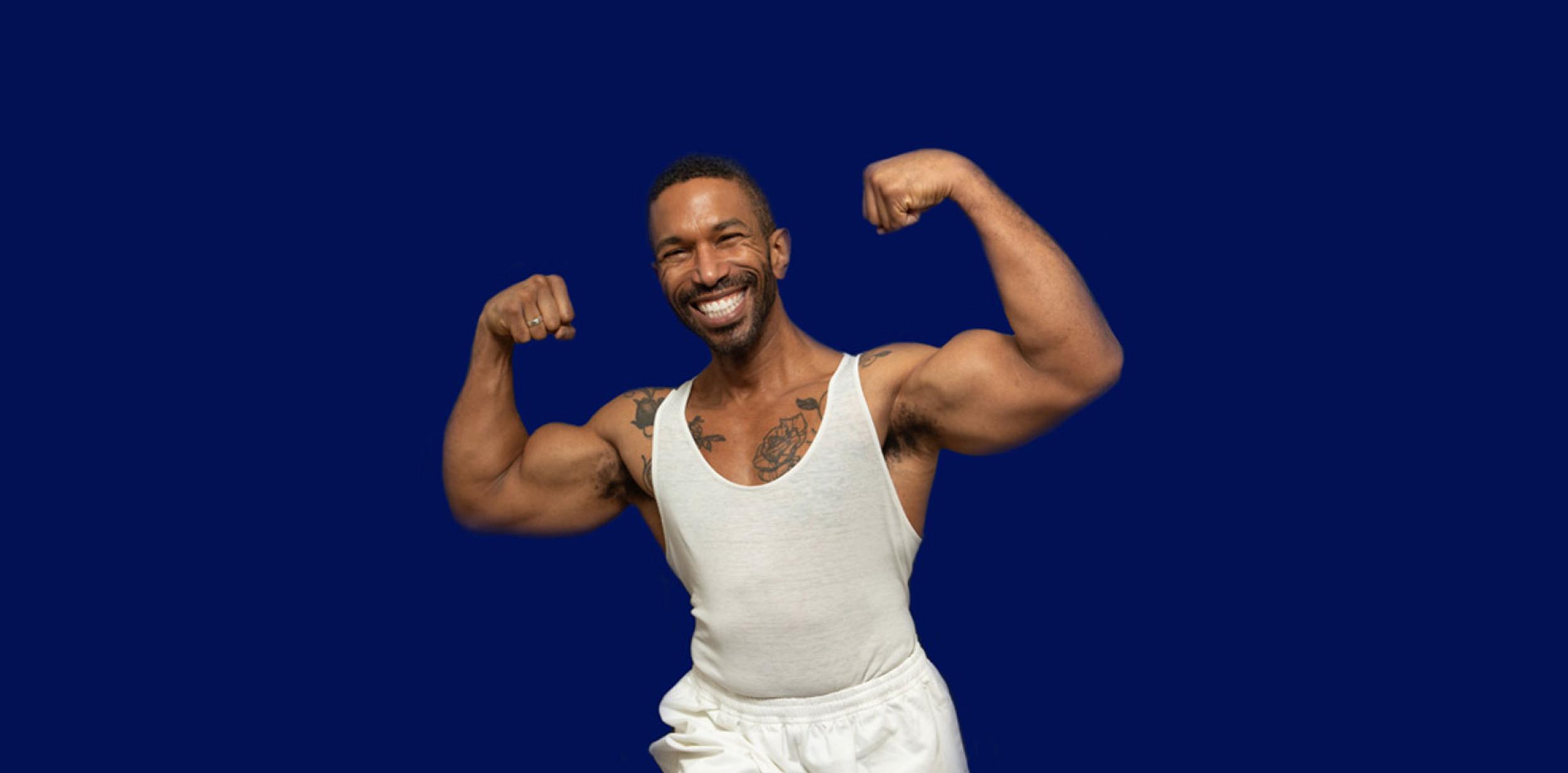 Man wearing a white vest flexing his arm muscles