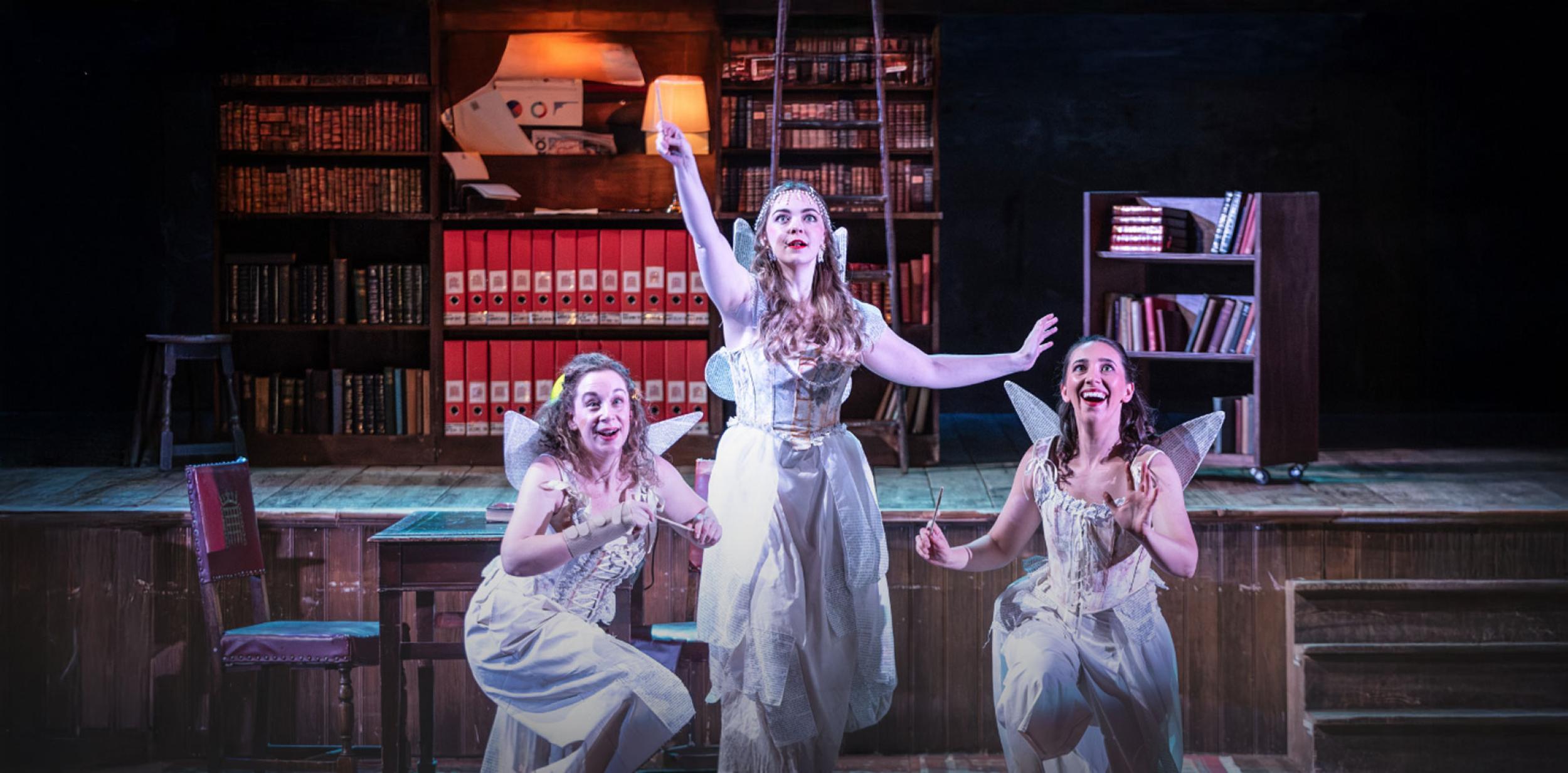 Three people on a stage dressed as fairies
