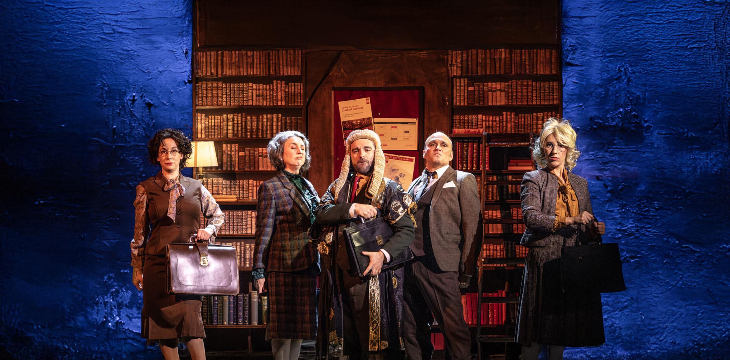 A group of people in period costume standing infront of a large bookcase