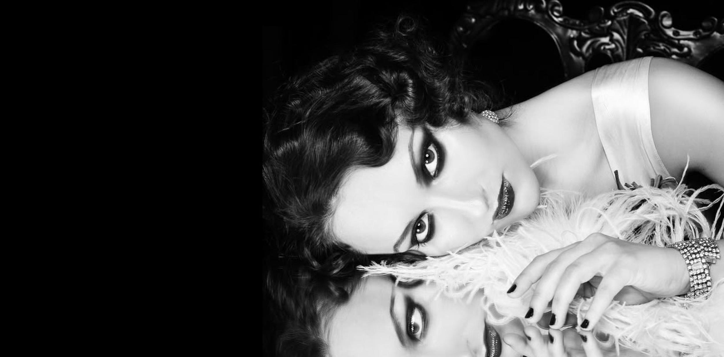 A woman in a cocktail dress, resting their face on a reflective surface