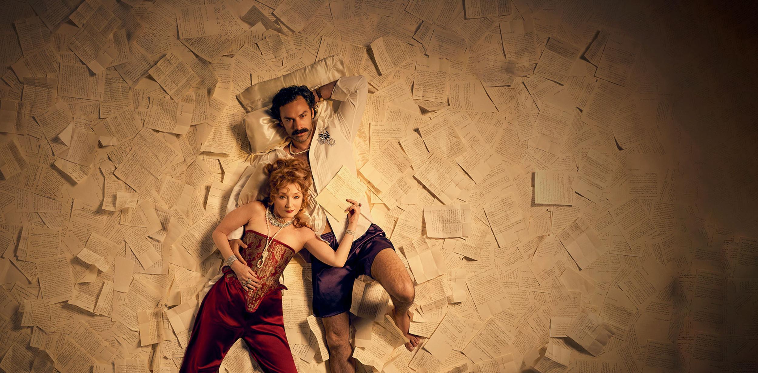 Two people laying down on a large pile of letters