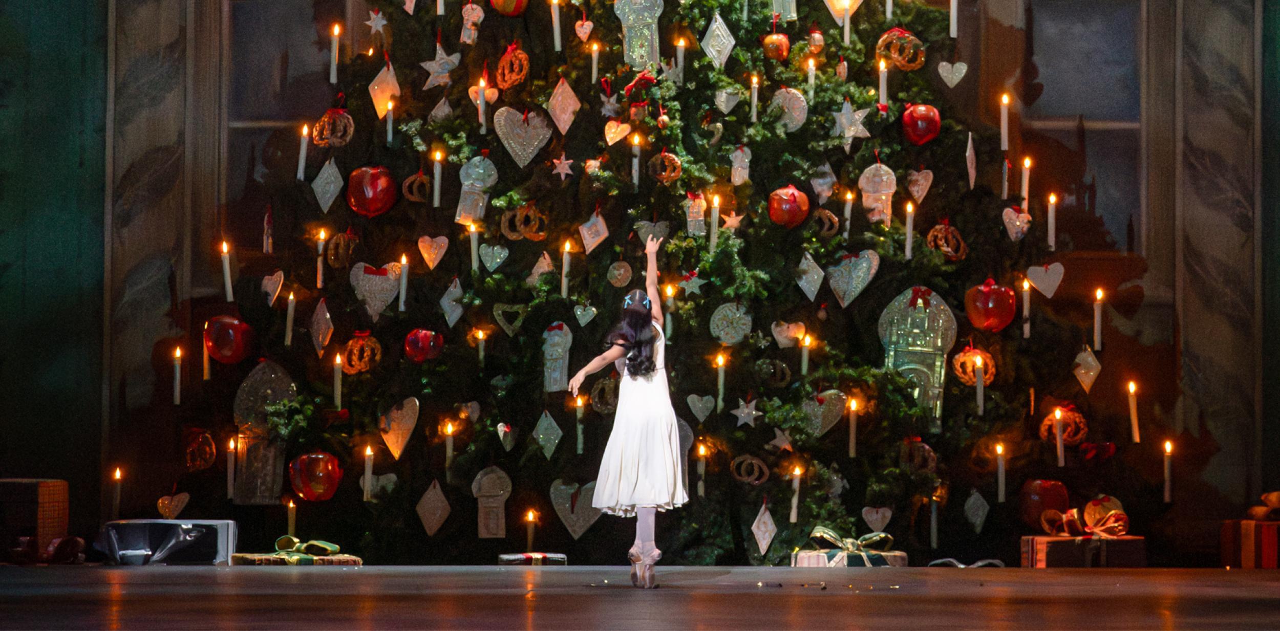 A ballet dancer reaching up to a giant Christmas tree
