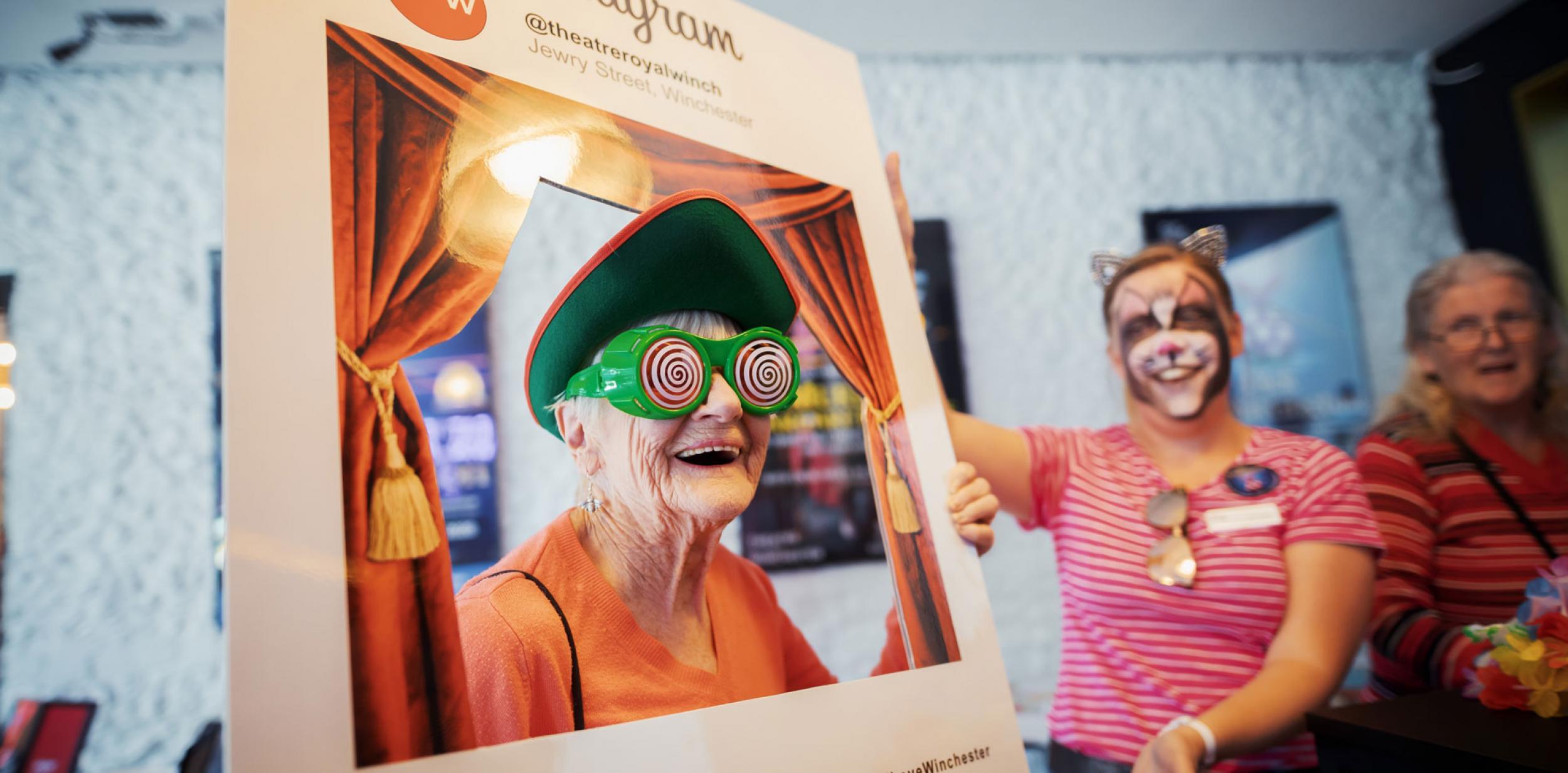 Lady with comic glassed looking through a selfie board