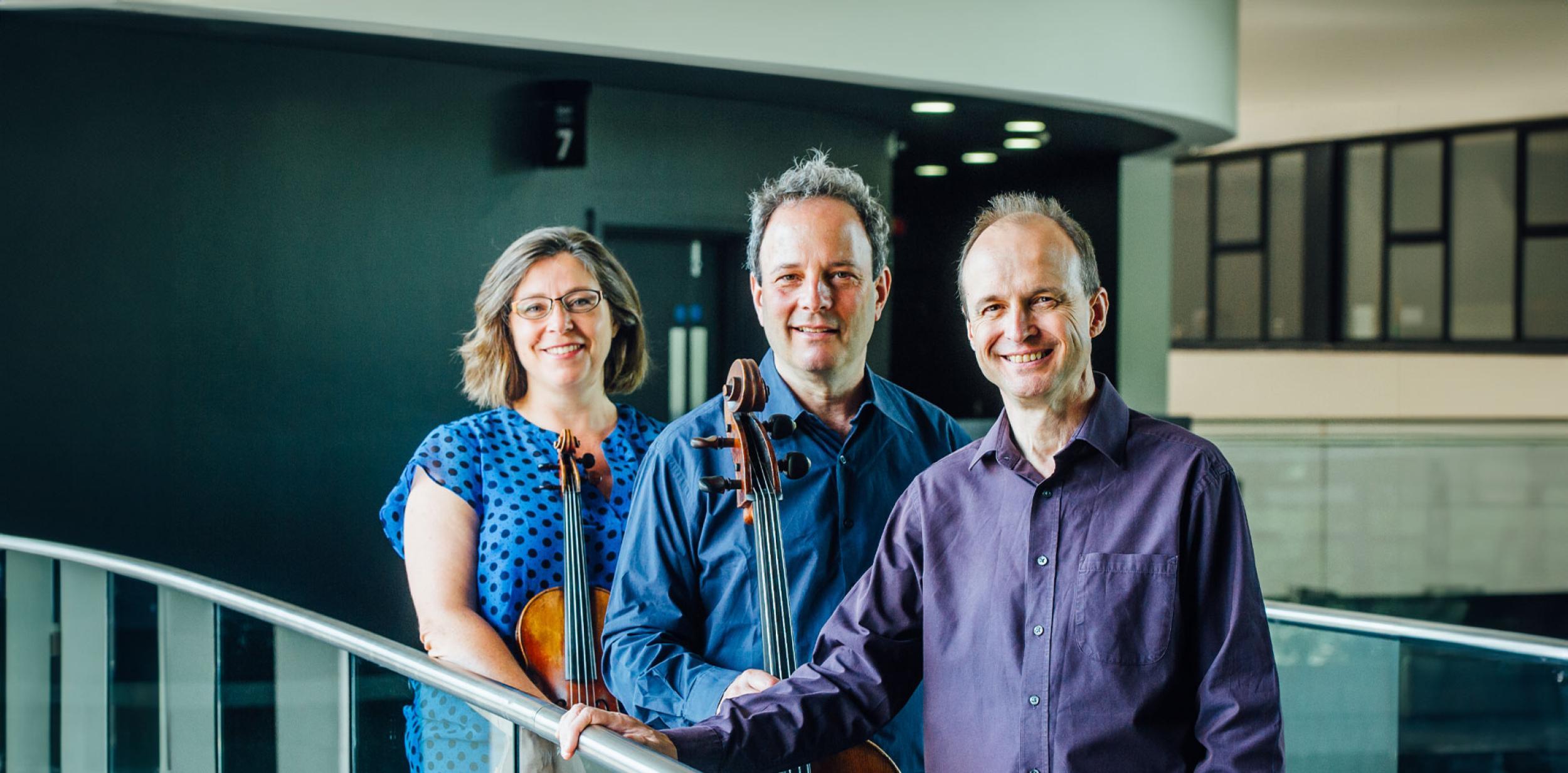 Three people holding string instuments