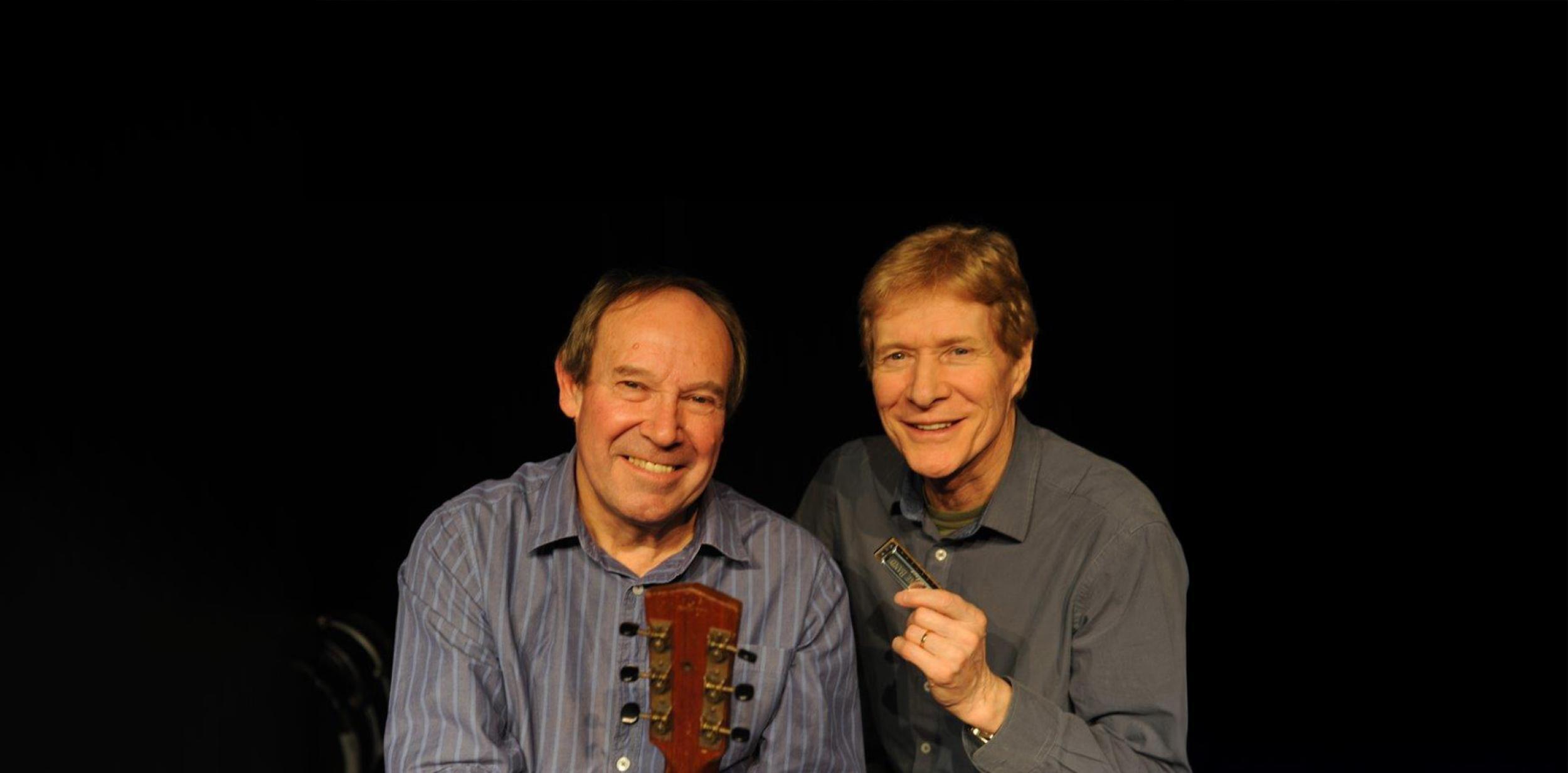 Paul Jones and Dave Kelly smiling with a dark background.