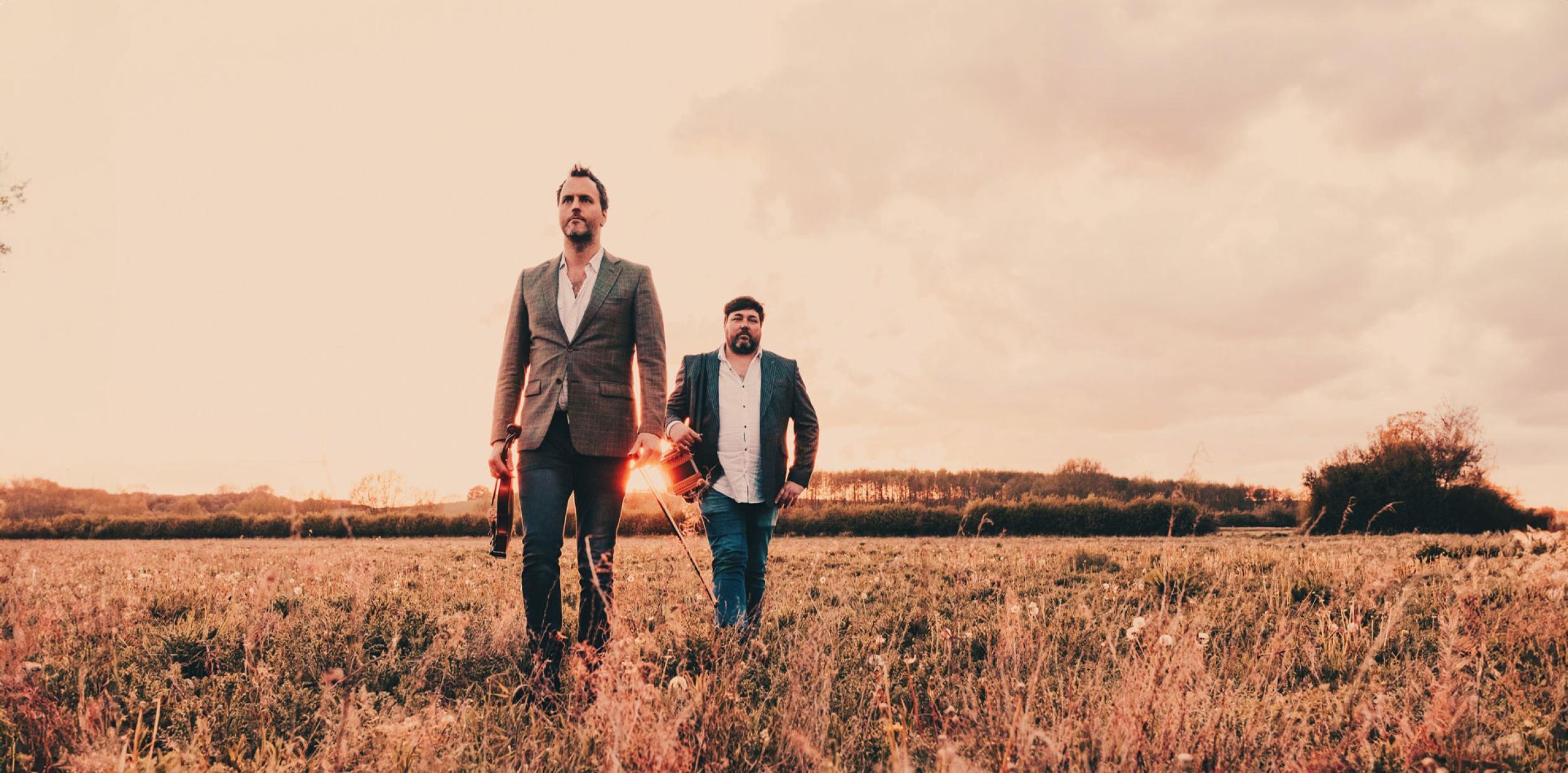 Two people in a field with musical instruments