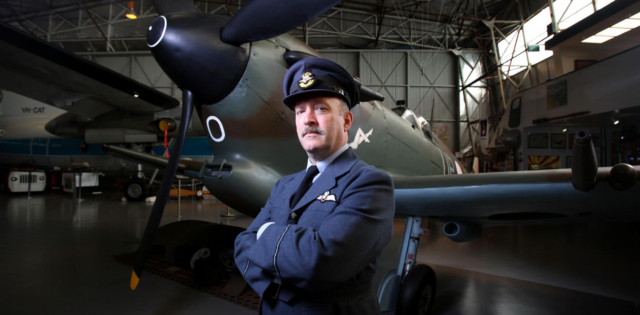 A pilot standing in front of a spitfire plane.
