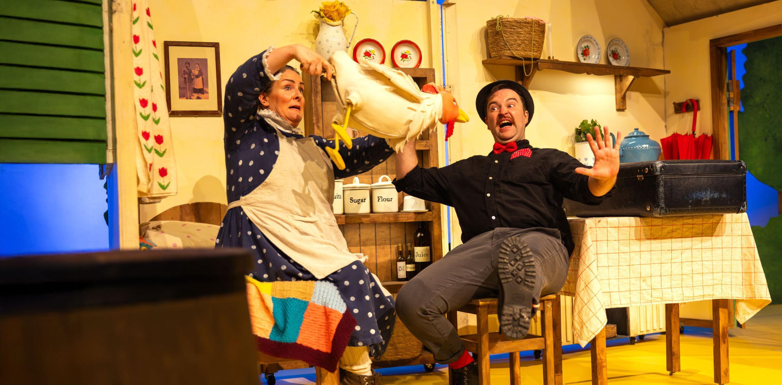 Two people and a chicken puppet in a farmhouse kitchen