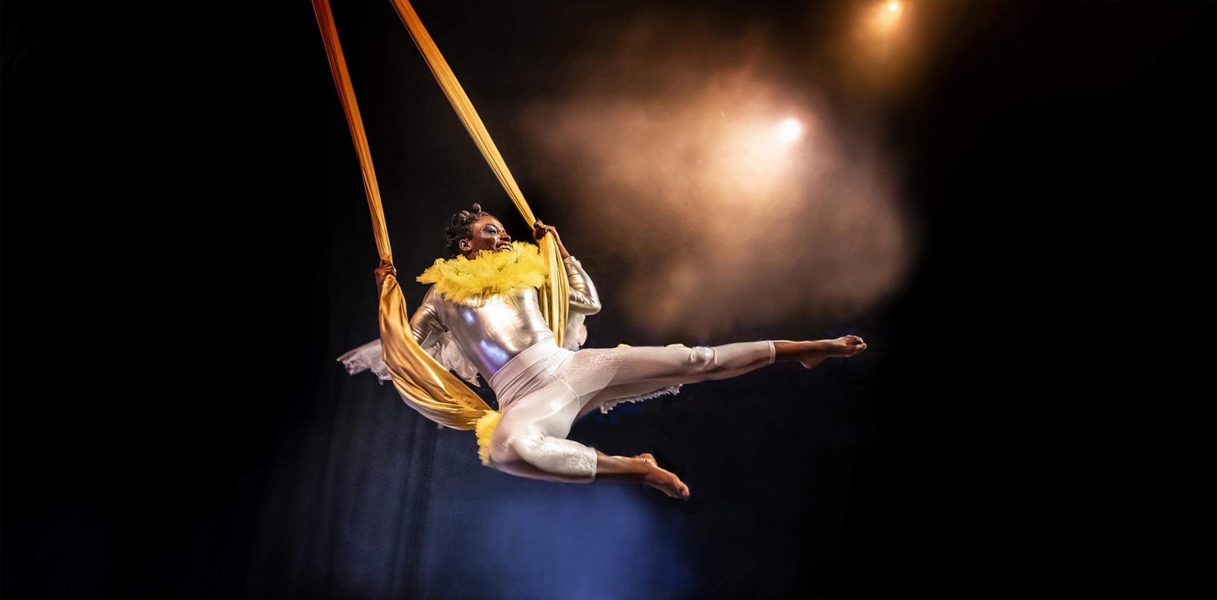 Aerial performer swinging on fabric and looking happy.
