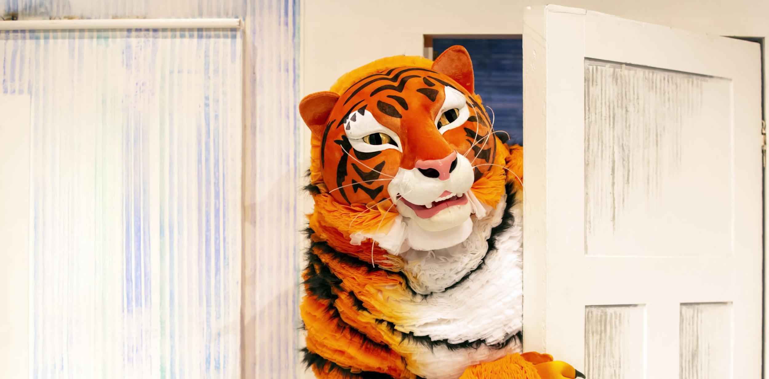 A tiger peering around a door.