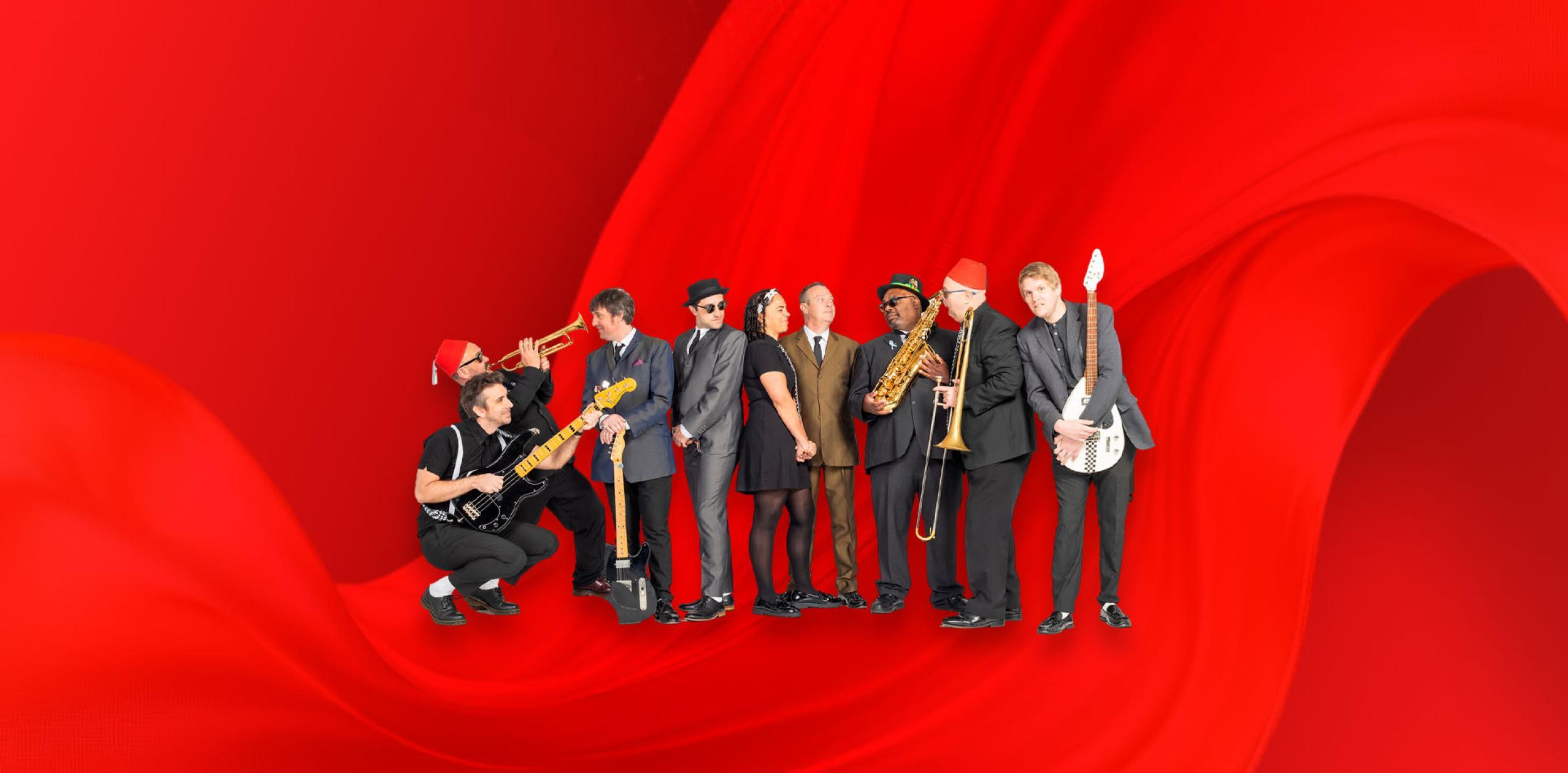 A group of musicians stood in front of a red background.