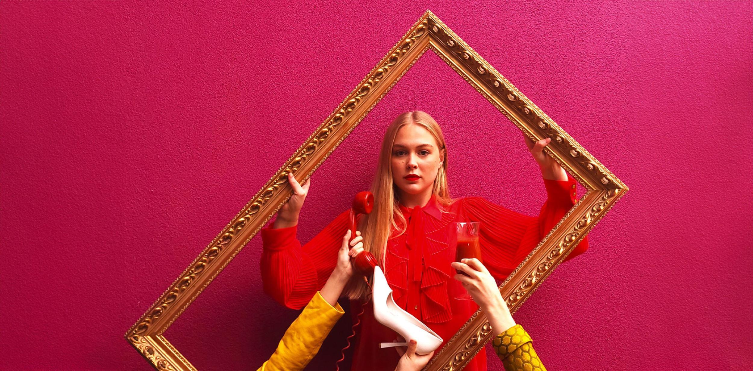 A person holding up and looking through and large picture frame