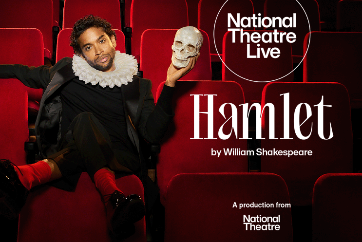A person sitting in a theatre seat, holding a skull