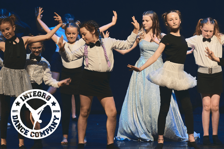 Young people dancing on stage with Integr8 logo