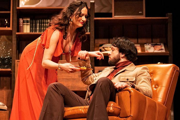 A person in a red dress serving drinks to another person sat in a chair