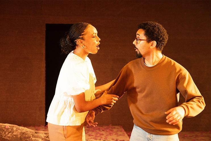 A woman grabbing hold of a man's arm looking serious.