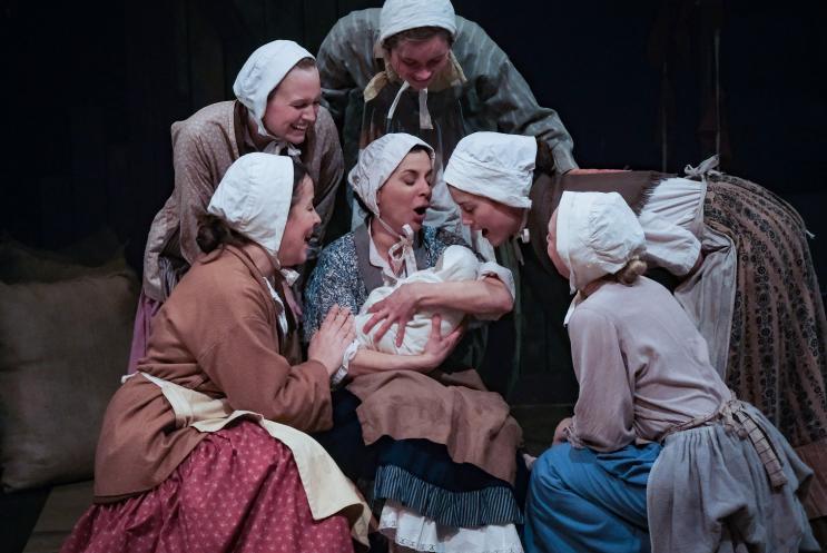 A group of girls huddled around a baby