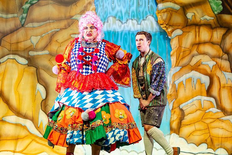 Panto Dame looking confused and hero Colin looking scared, stood in front of a waterfall backdrop.