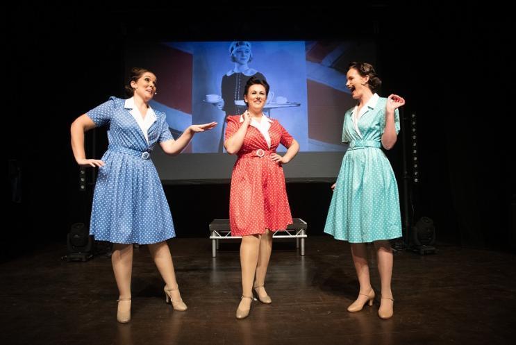 3 female singers in 1930s fashion on a stage