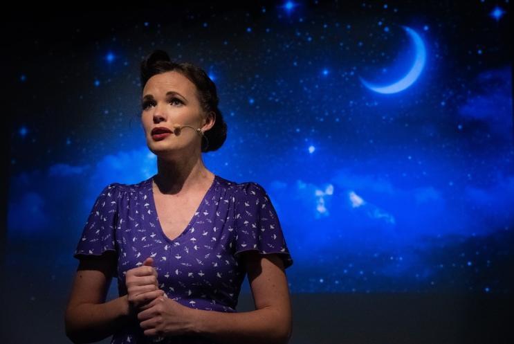 female singer in front on a starry night time sky