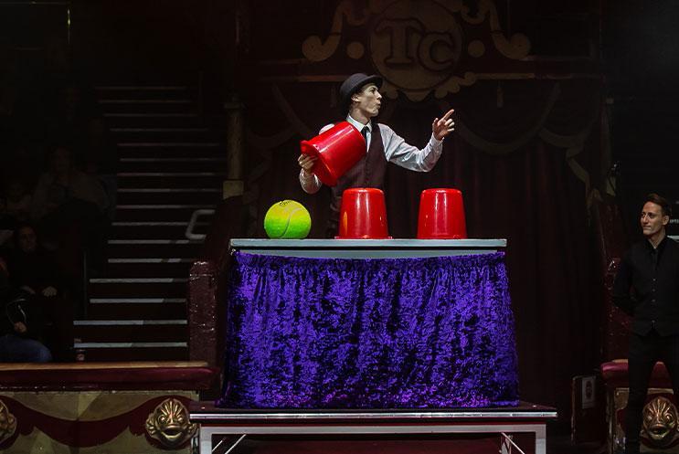 A person performing a magic trick with giant buckets