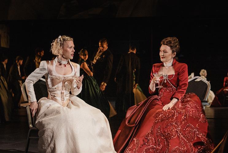 Two performers in dresses sat talking to each other.