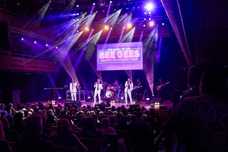 An audience watching three performers on stage singing