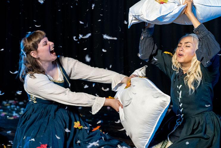 Two people pillow fighting