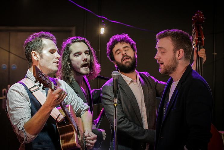 Four musicians stood together singing