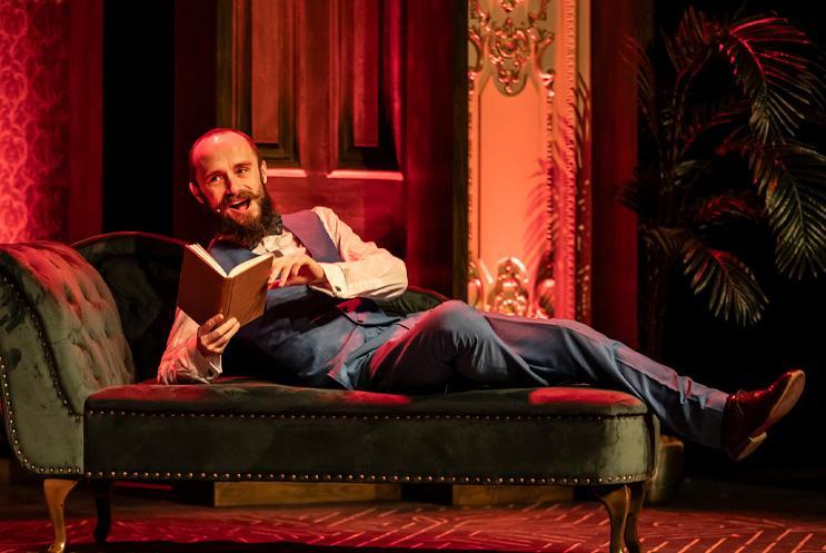 Man lying on a chaise longue with a book.
