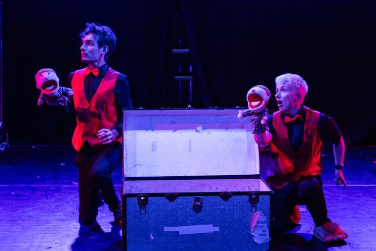 Two performers knelt beside a chest with puppets