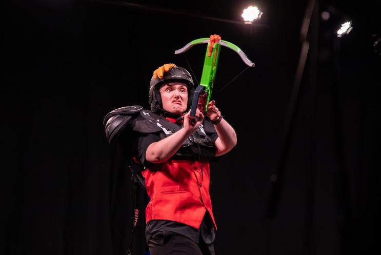 A performer looking fierce with a toy crossbow.
