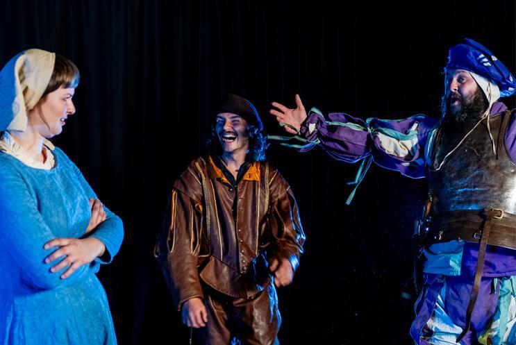 Three performers stood laughing
