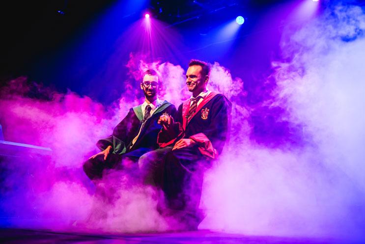 Actors dressed as wizards sat on stage amidst purple smoke