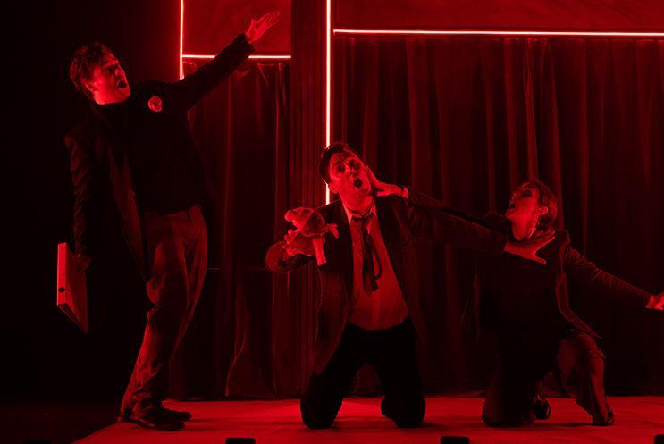 Three performers looking scared is red lighting