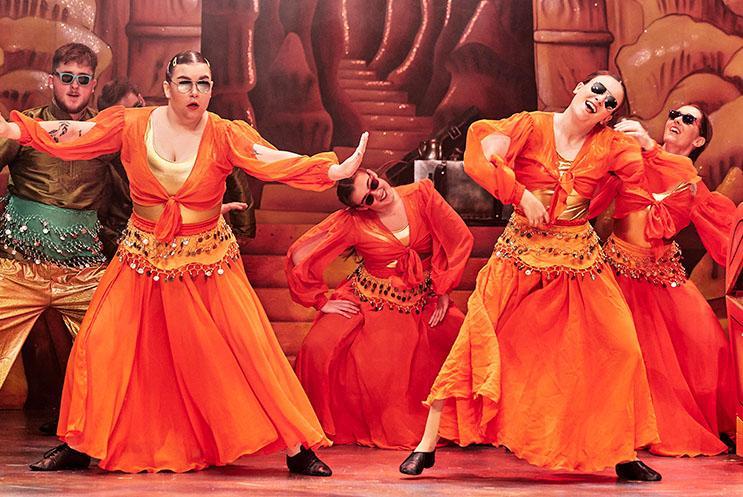 A group of young people dressed in Arabian costume dancing on stage