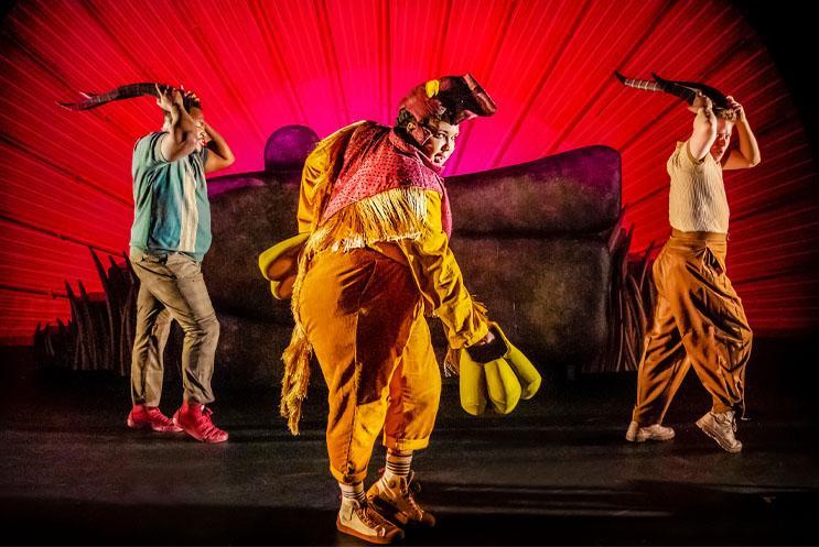 Three performers dressed as animals and dancing with a sunset in the background.
