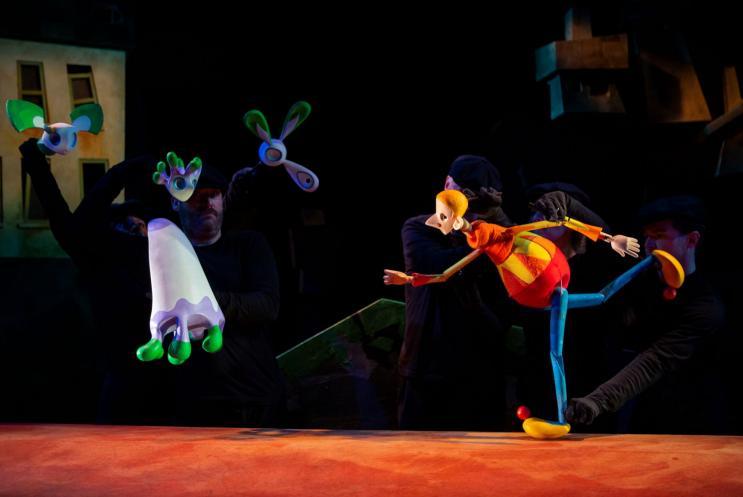 a male puppet running across the stage