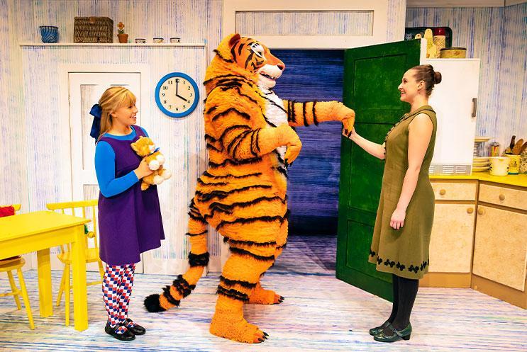 A person in a tiger costume shaking hands with another person