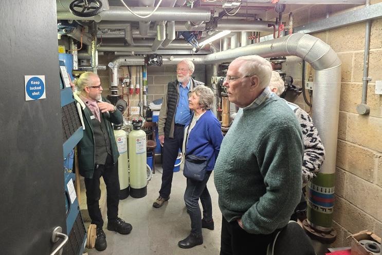 A group gathered in the boiler toom under the stage, listening to the site manager talk