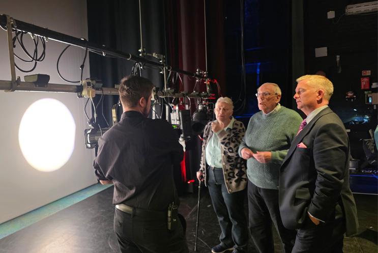 A group gathered in the stage looking at lighting equipment