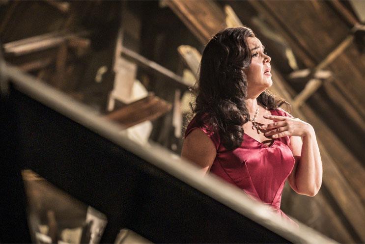 A woman singing with her hand on her chest.