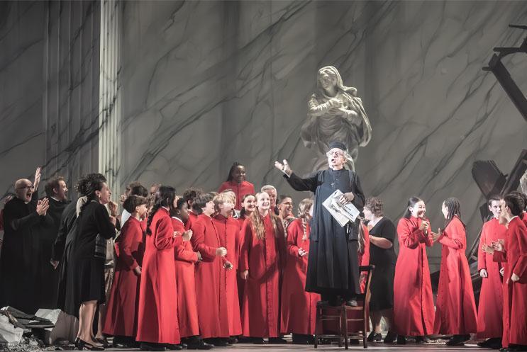 Priest giving a speech to a crowd dressed in black and red robes.